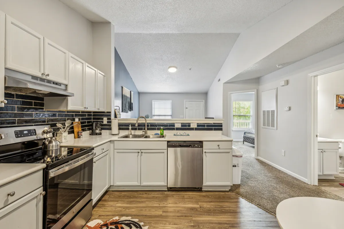 An inviting kitchen scene centered on a kitchen island, complemented by sleek stainless steel appliances and a blue accent wall. The layout is practical for cooking, with generous prep space and an open feel ideal for hosting and family interaction.