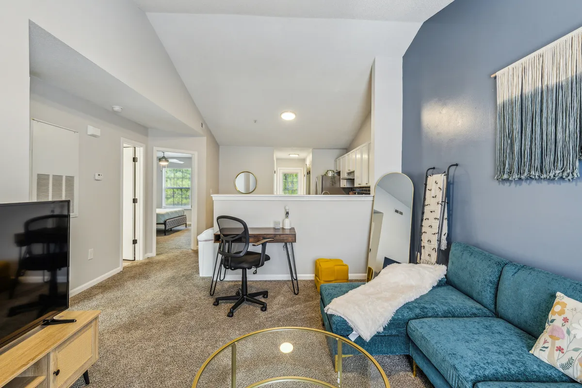 This cozy interior image reveals a welcoming living area with a sofa, coffee table, desk, and open kitchen. The multifunctional space is perfect for relaxing, entertaining, or preparing a meal after experiencing the city.